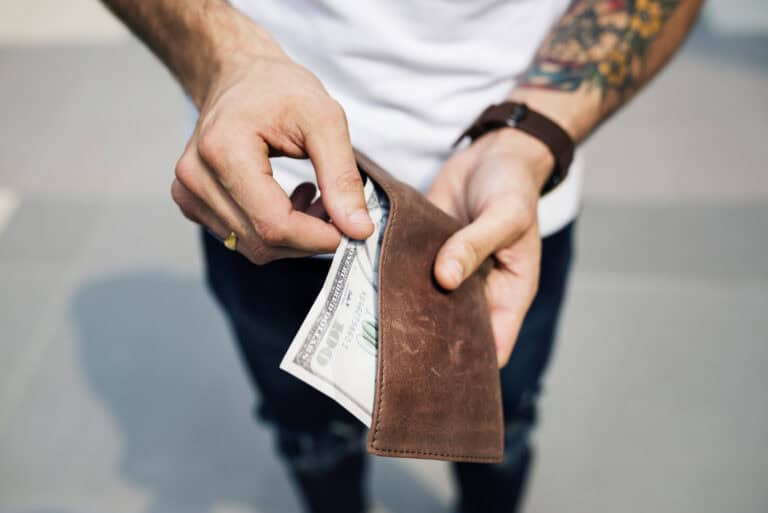 Person holding a wallet with cash, emphasizing flood insurance affordability and risk protection.